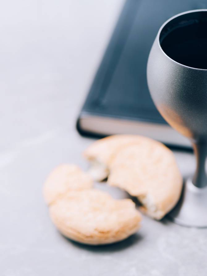Unleavened bread, chalice of wine, Holy Bible on grey background. Christian communion for reminder of Jesus sacrifice. Easter passover. Eucharist concept. Christianity symbol and faith.